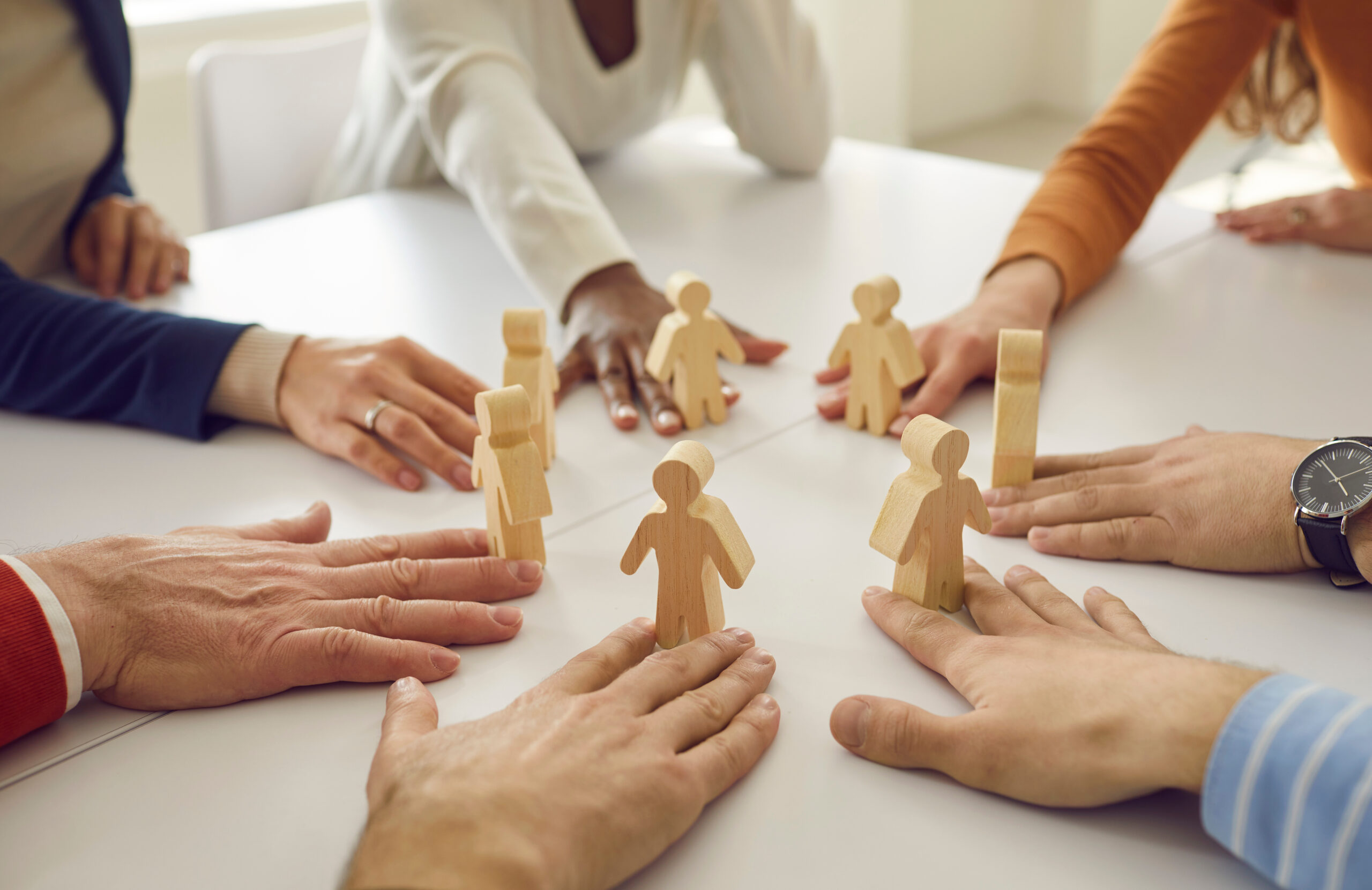Team of business people put little human figures in circle as symbol of community and teamwork